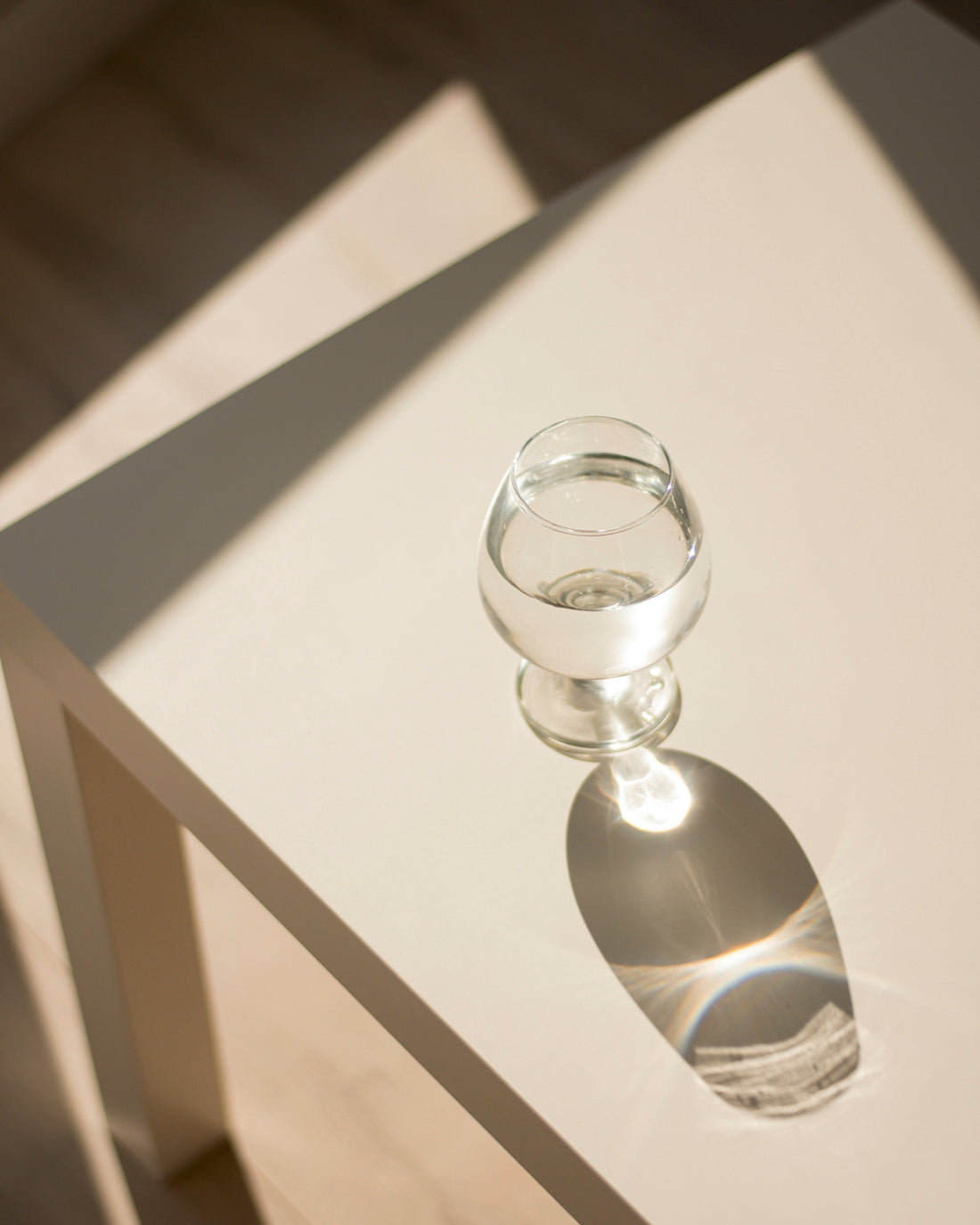 Rose hydrosol water in a clear glass on a beige table 