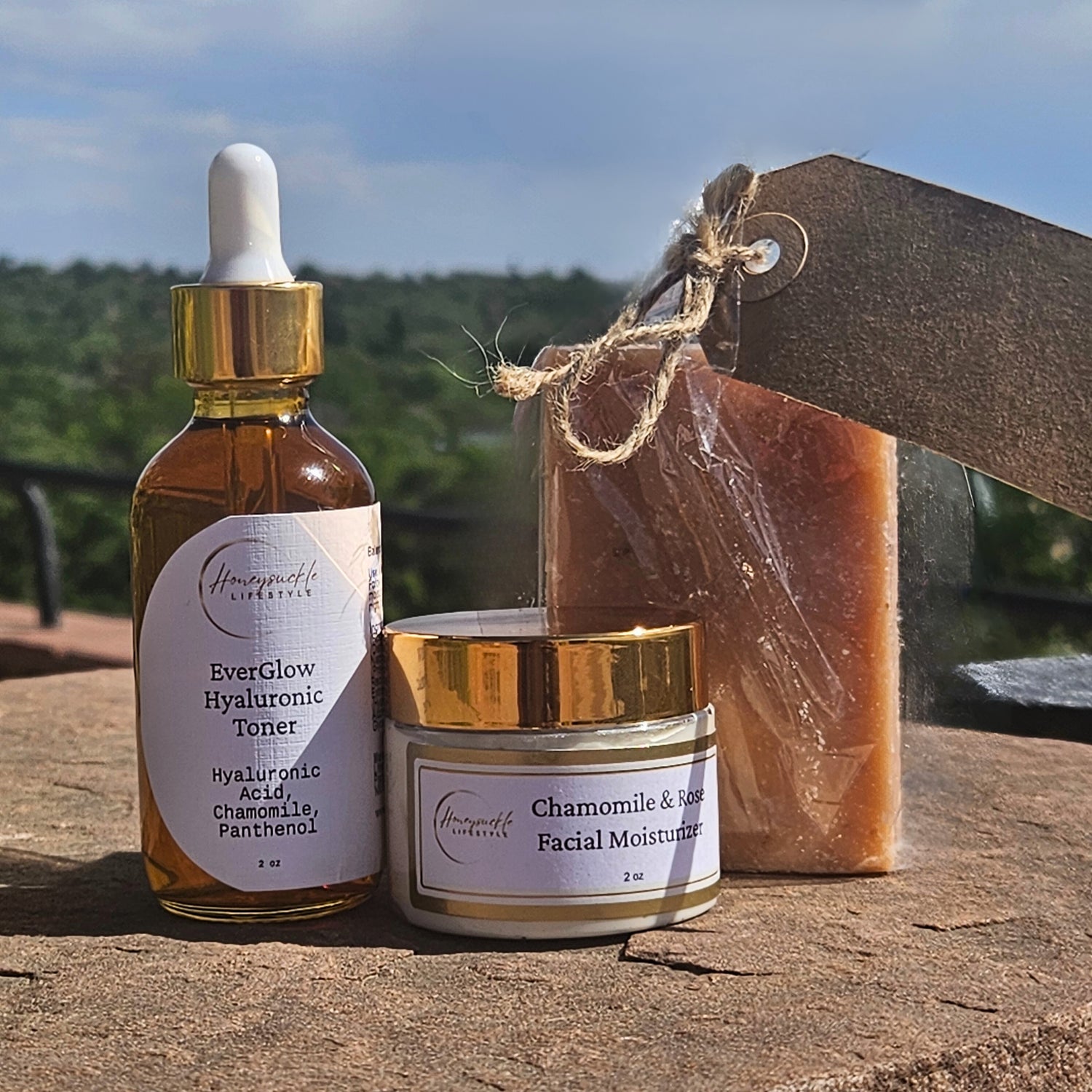 Cosmetic products including a dropper bottle, jar, and bar of soap with a natural background.