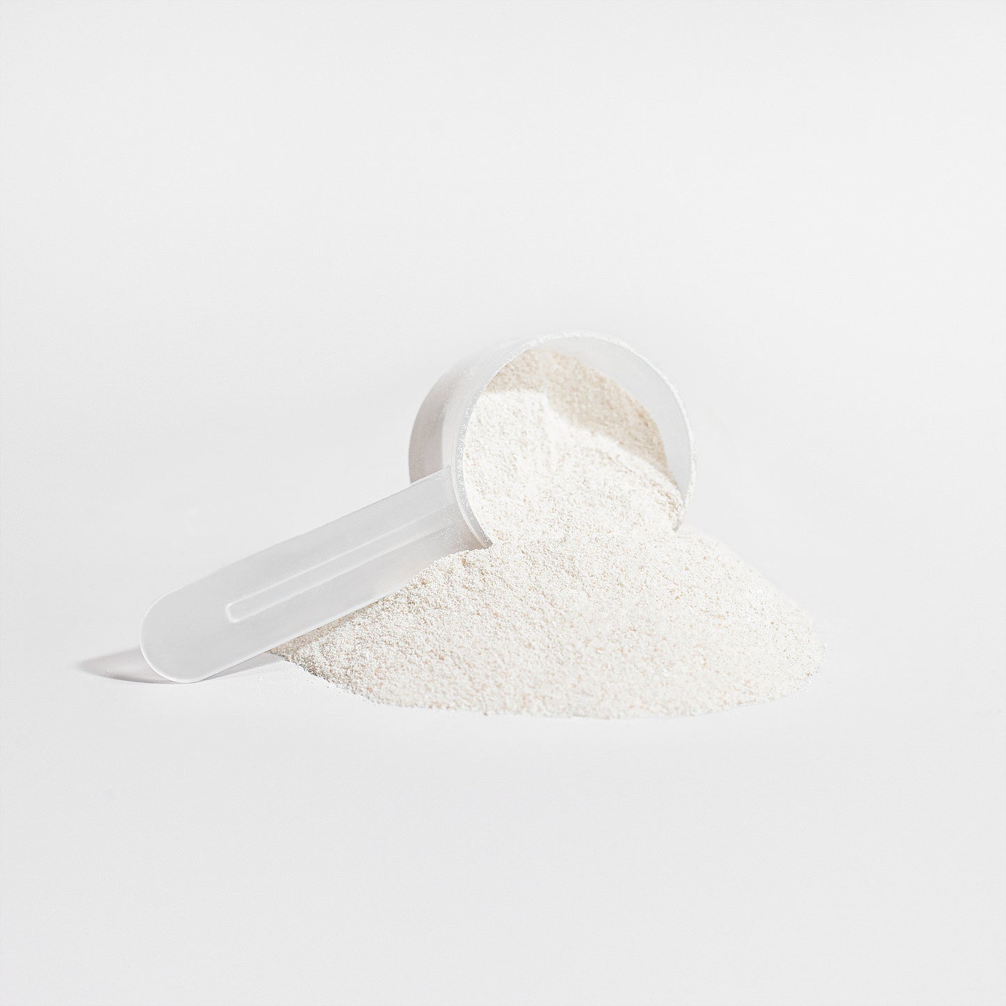 White powder in a clear plastic scoop on a light gray background
