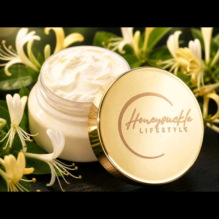 HoneySuckle Whipped Butter in a clear container signature gold lid and logo on a HoneySuckle flower filled background 