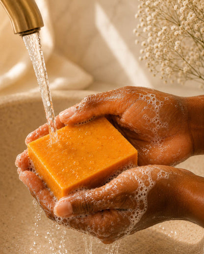 Hands washing a bar of soap under running water with a soft focus background